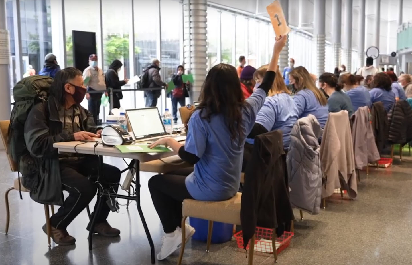 People sitting at a line of computer stations, being checked in for an appointment.